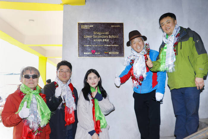 현대오일뱅크 1%나눔재단 직원들과 산악인 엄홍길 씨(왼쪽 네번째)가 네팔 고르카 지역 버거워띠 중학교 준공식에서 현판을 걸고 기념촬영했다.