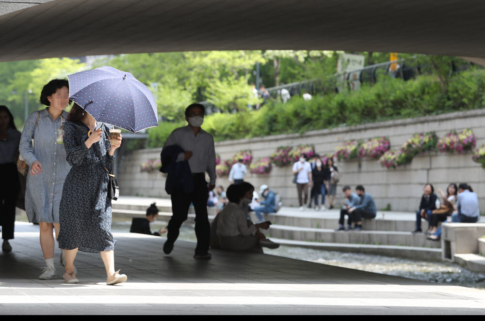 서울 낮 최고 기온이 26도를 기록한 4일 오후 서울 청계천에서 양산을 든 시민이 걸어가고 있다. <연합뉴스>