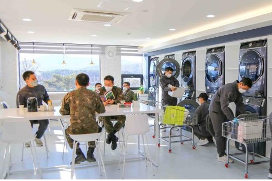 육군 51사단 장병들이 병영세탁방에서 세탁기와 건조기를 이용하고 있다. 한쪽에서는 세탁물 회수를 기다리는 장병들이 휴식을 취하고 있다.(사진=국방부)
